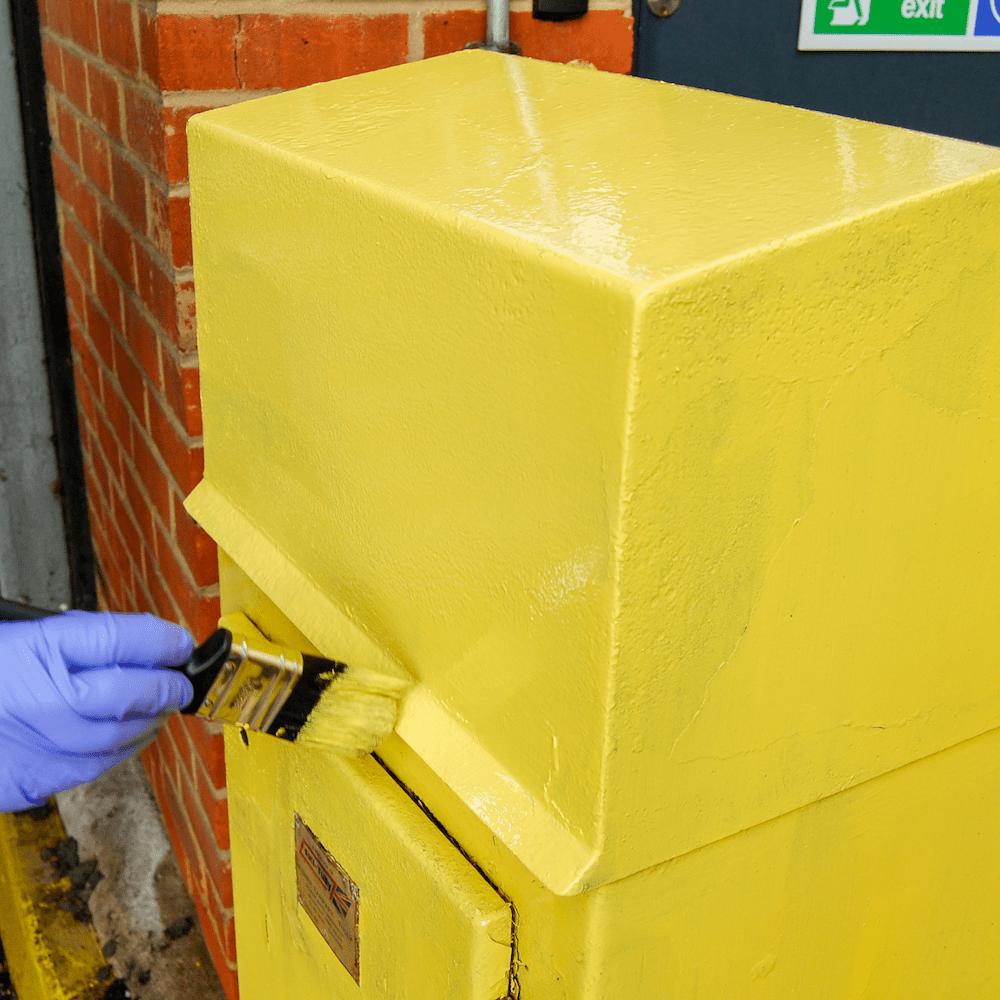 Multi-purpose paint yellow being applied to a metal surface by brush